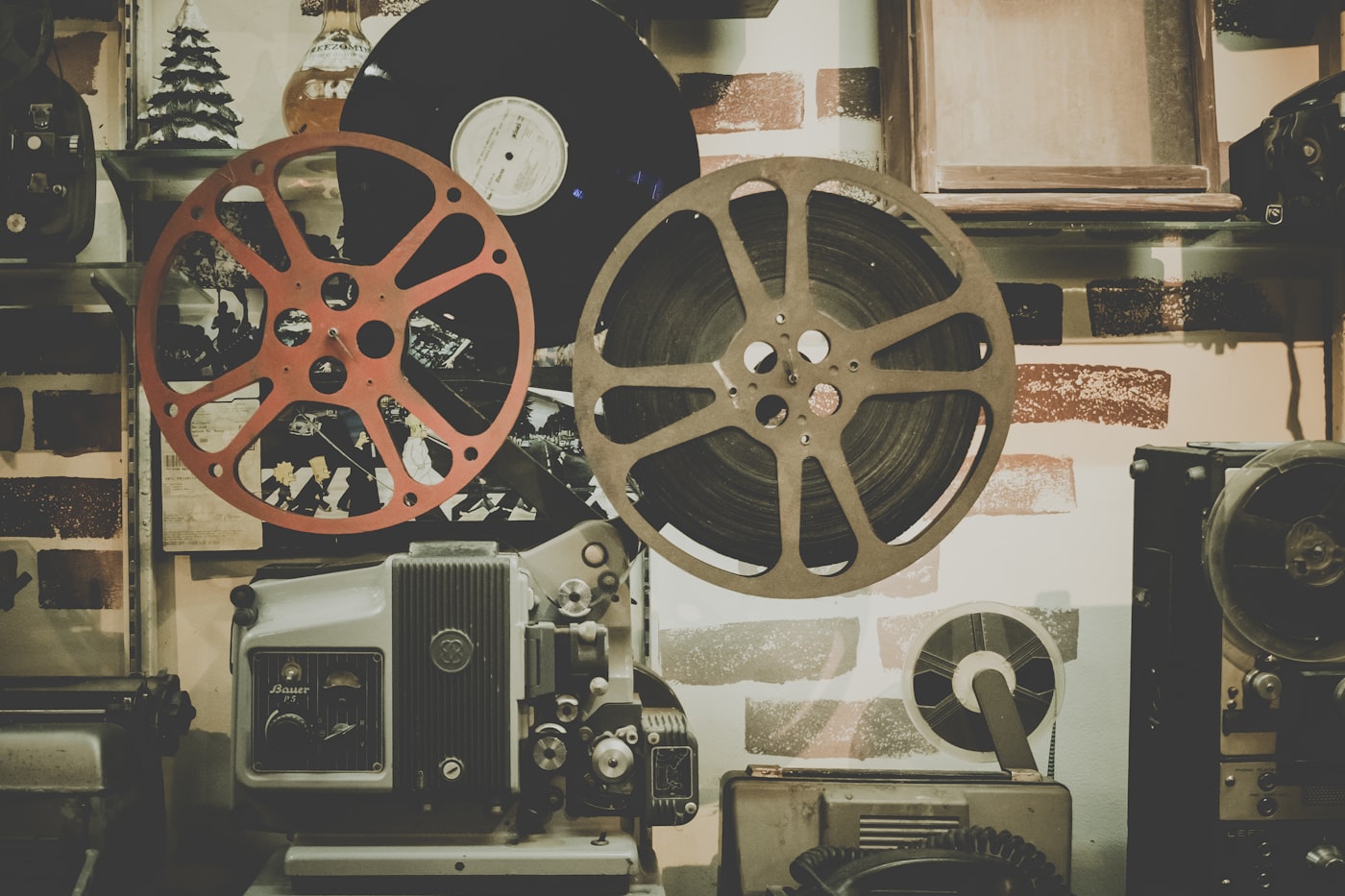 Vintage Bauer-projektor og filmspoler på en hylde foran en murstensvæg